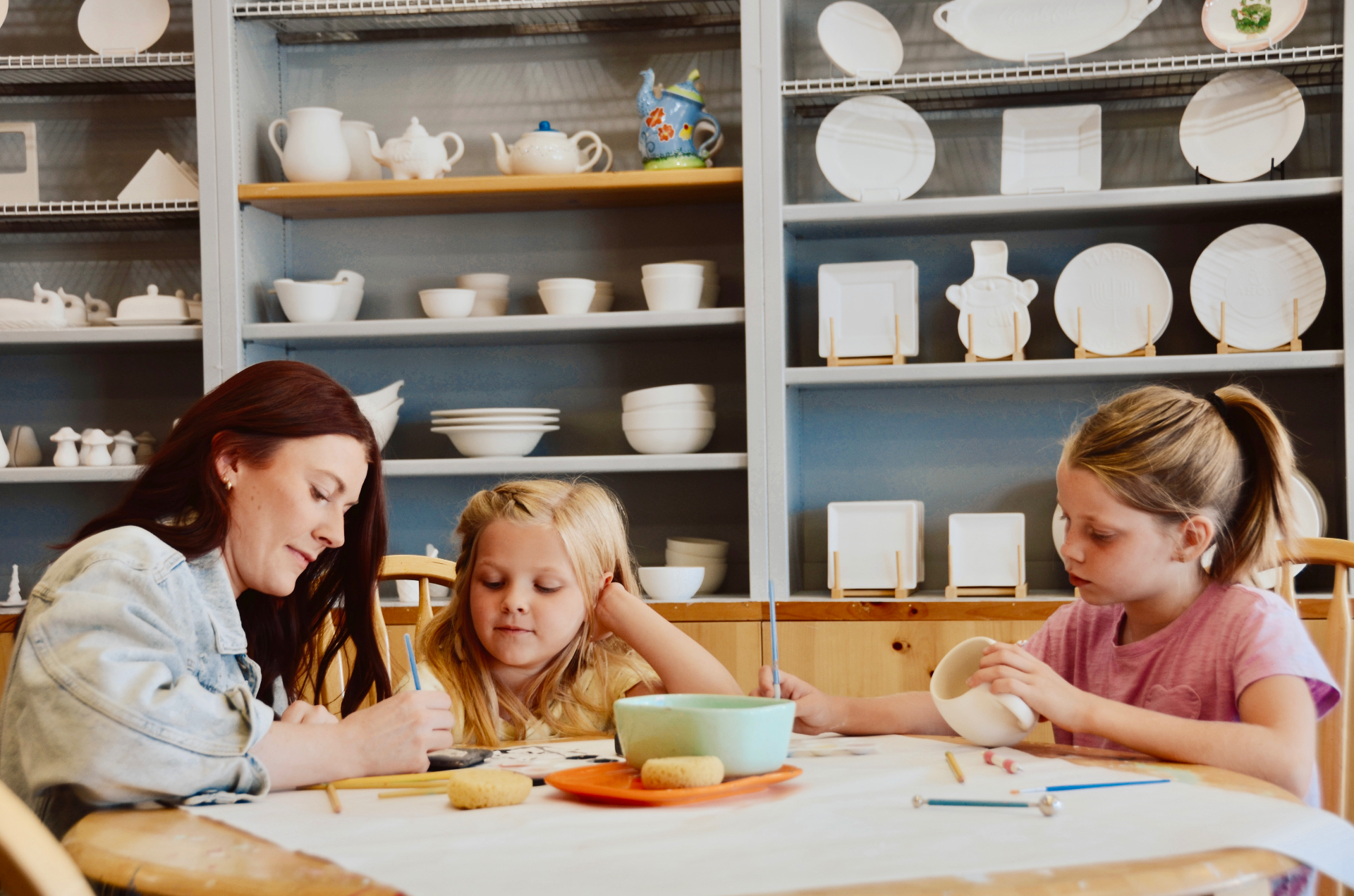 A mom and two kids painting pottery together at Paint Fusion Park City