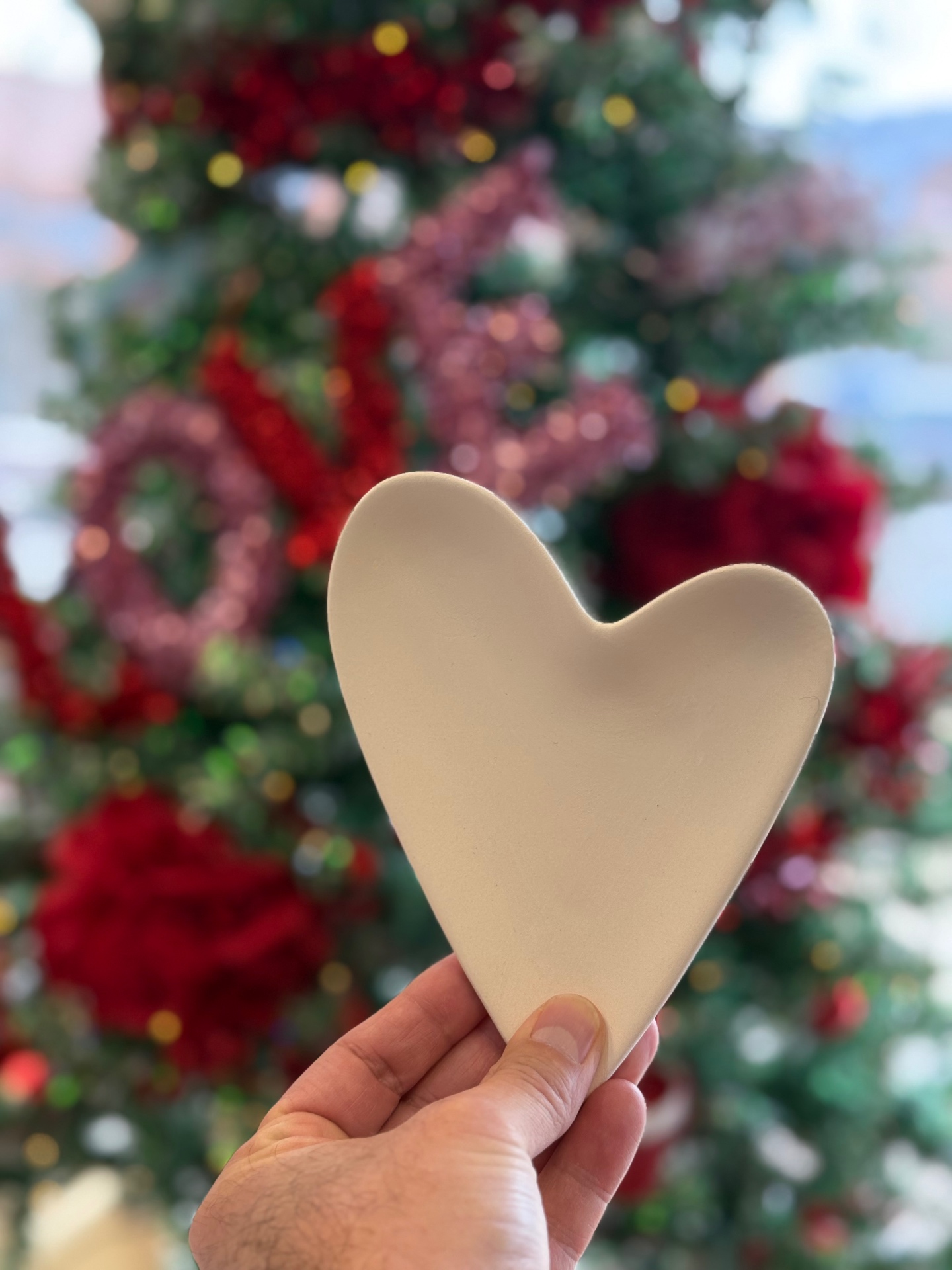 A ceramic heart dish held in front of the studio's holiday tree