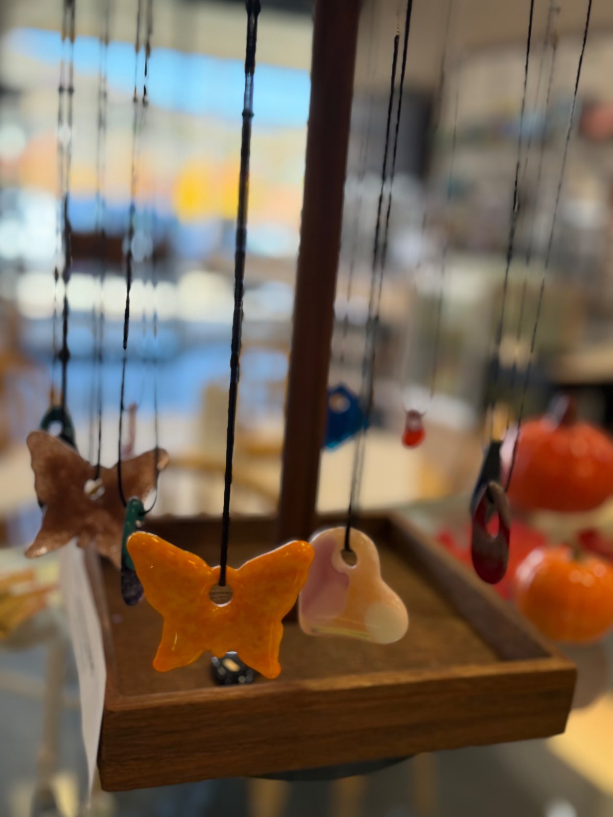 Display of colorful fused glass pendants at Paint Fusion