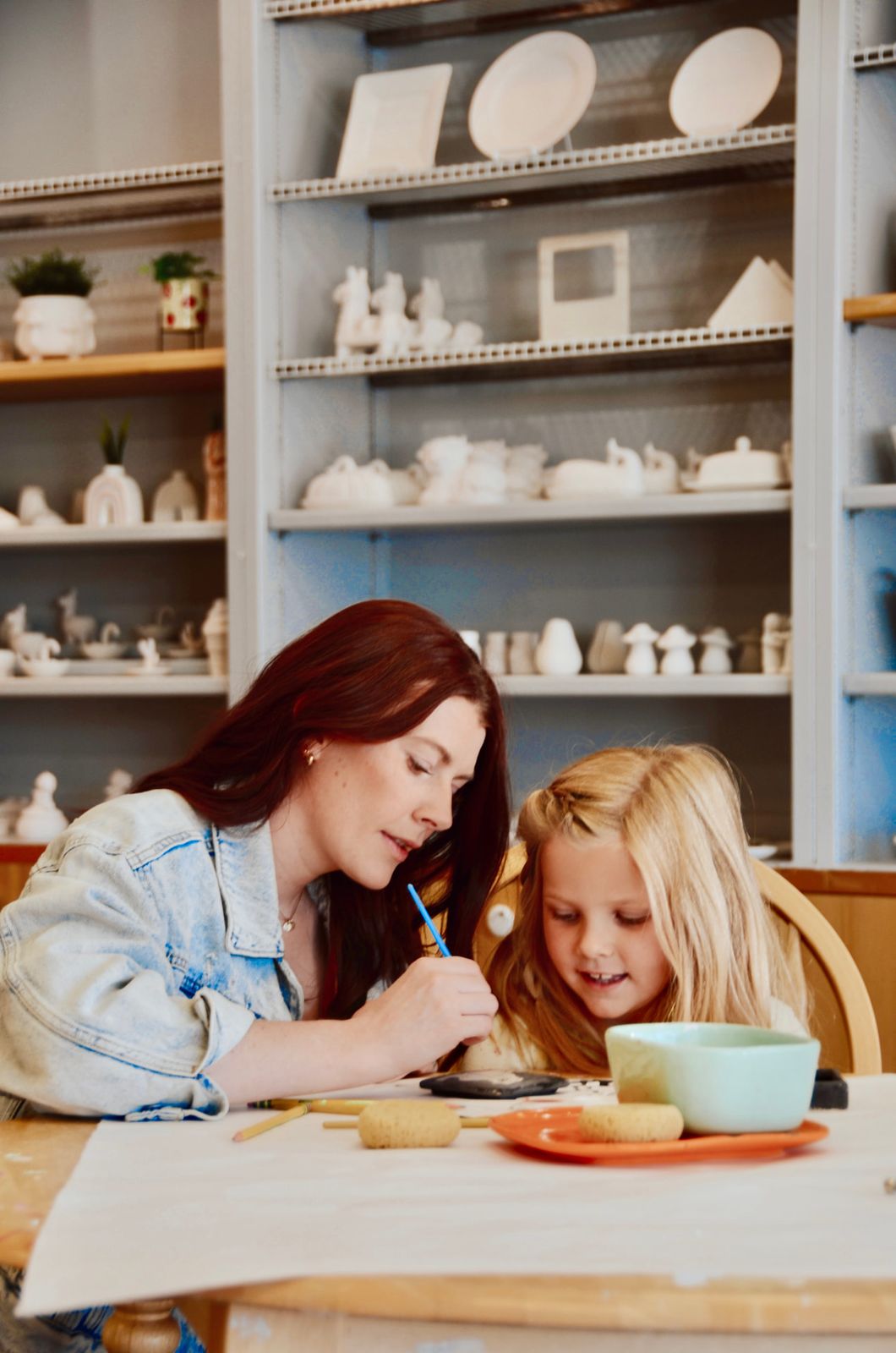 A mom helping her daughter paint pottery at Paint Fusion Park City