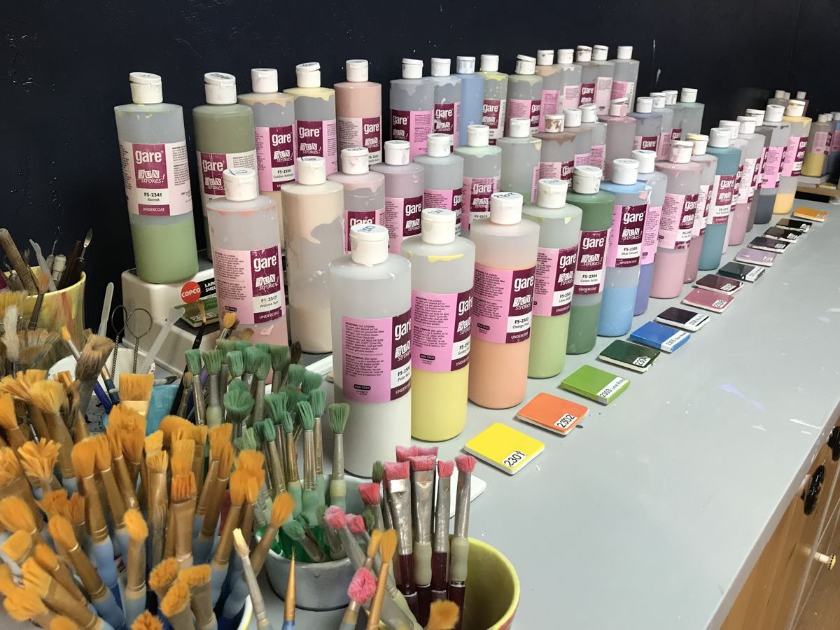 Rows of ceramic paint bottles and brushes in the Park City studio